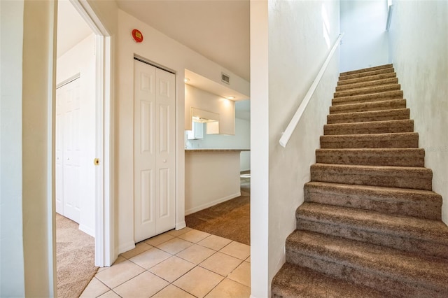 stairs with visible vents, carpet floors, and tile patterned flooring