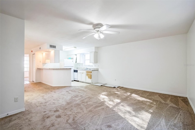 unfurnished living room with visible vents, light carpet, baseboards, and ceiling fan