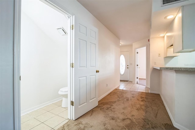 interior space featuring light tile patterned flooring, light colored carpet, and baseboards