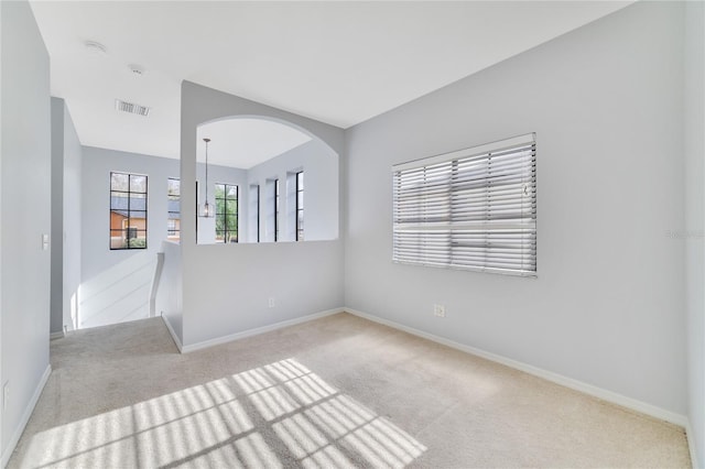 empty room with light carpet and a chandelier