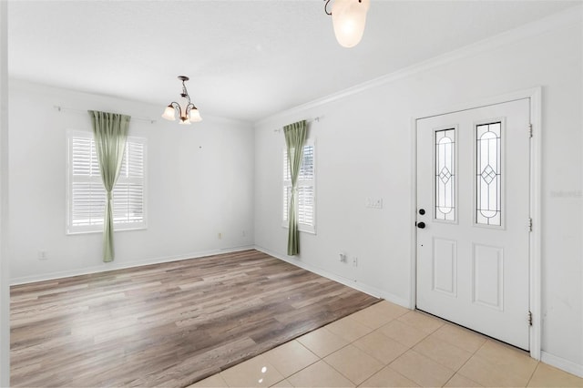 foyer with a notable chandelier, ornamental molding, a wealth of natural light, and light hardwood / wood-style flooring