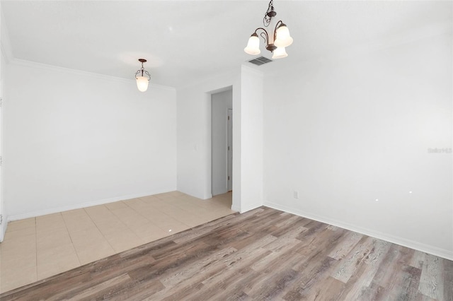 spare room with a chandelier, wood-type flooring, and crown molding