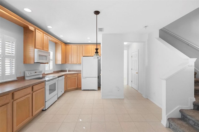 kitchen featuring light brown cabinetry, white appliances, hanging light fixtures, and light tile patterned flooring