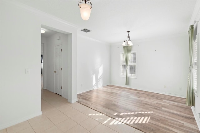 spare room featuring light wood-type flooring, crown molding, and a chandelier