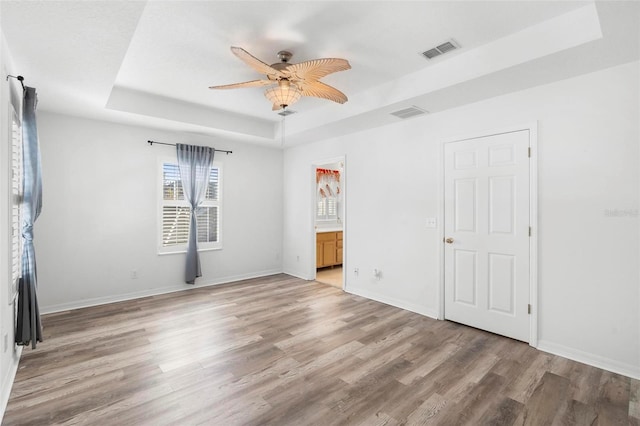 unfurnished room featuring a raised ceiling, ceiling fan, and wood-type flooring