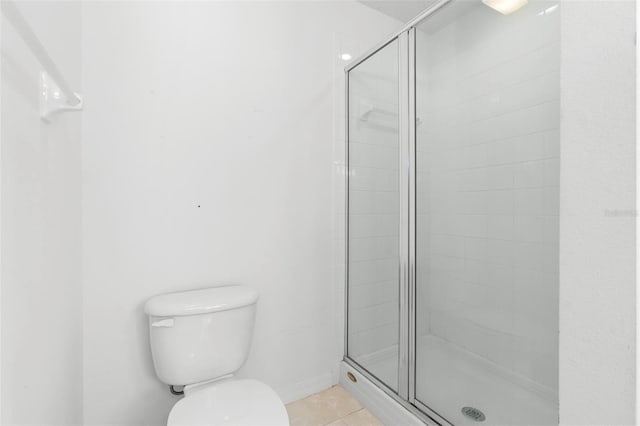 bathroom with tile patterned flooring, a shower with shower door, and toilet