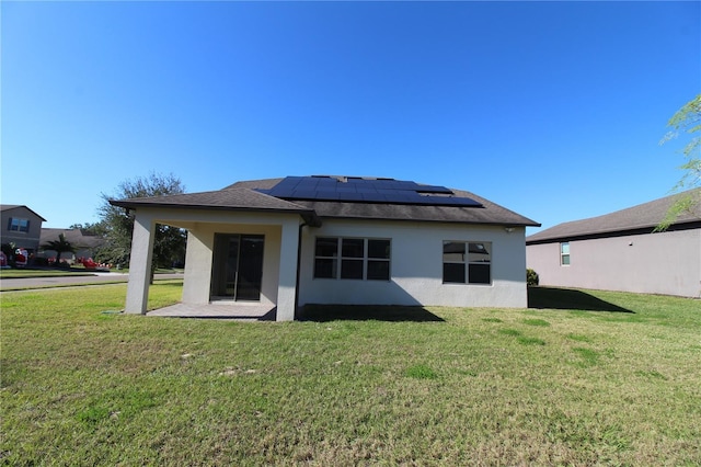 rear view of house featuring solar panels and a yard