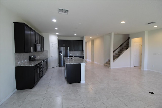 684 Bishop Bay Loop, Apopka, FL 32712 - kitchen featuring stainless steel appliances, dark cabinetry, decorative backsplash, light stone counters, and open floor plan