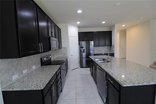 684 Bishop Bay Loop, Apopka, FL 32712 - kitchen with appliances with stainless steel finishes, dark cabinets, a spacious island, decorative backsplash, and light tile patterned flooring