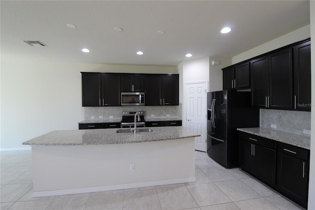 kitchen with appliances with stainless steel finishes, backsplash, a center island with sink, and sink