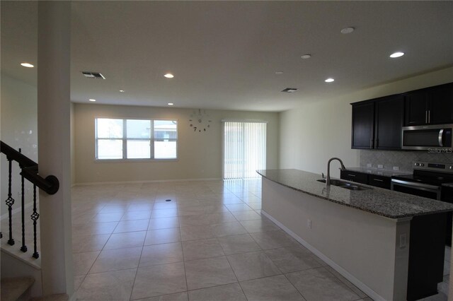 684 Bishop Bay Loop, Apopka, FL 32712 - kitchen with stainless steel appliances, backsplash, stone counters, recessed lighting, and a center island with sink