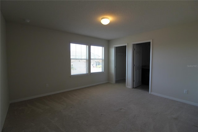 unfurnished bedroom featuring a walk in closet, a closet, and carpet