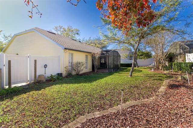 view of side of home with glass enclosure and a lawn