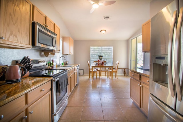 kitchen with light brown cabinets, sink, stainless steel appliances, tile patterned flooring, and stone countertops