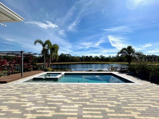 view of swimming pool featuring an in ground hot tub, a pergola, a water view, and a patio area