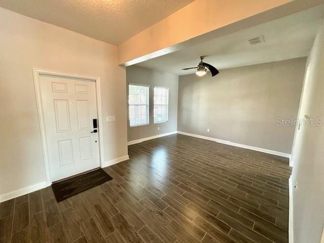 foyer with ceiling fan, dark wood-type flooring, and a textured ceiling