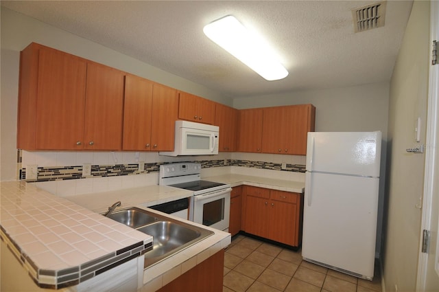 kitchen featuring a textured ceiling, white appliances, sink, light tile patterned floors, and tile countertops