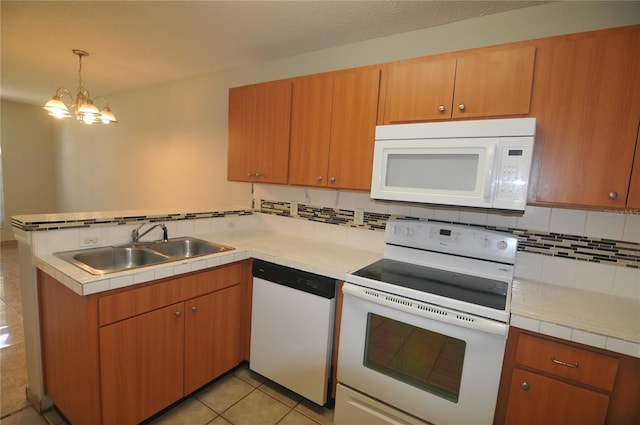 kitchen featuring kitchen peninsula, white appliances, sink, an inviting chandelier, and hanging light fixtures