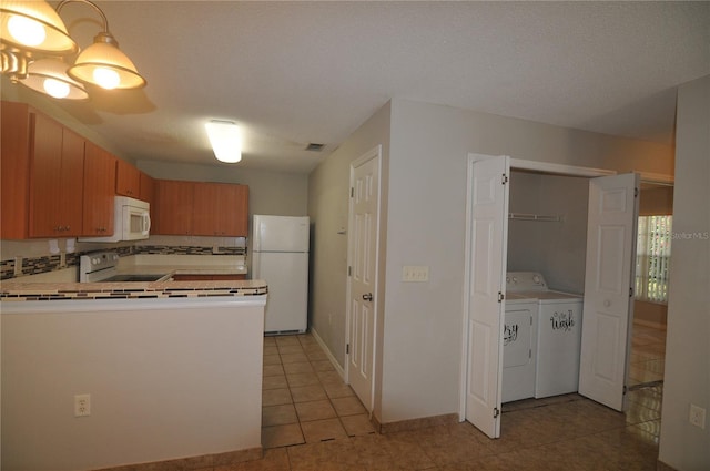 kitchen featuring washer and clothes dryer, white appliances, decorative backsplash, light tile patterned floors, and a textured ceiling