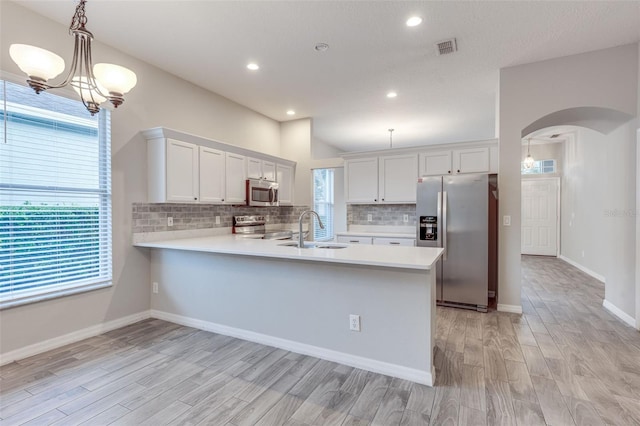 kitchen featuring white cabinets, sink, stainless steel appliances, and hanging light fixtures