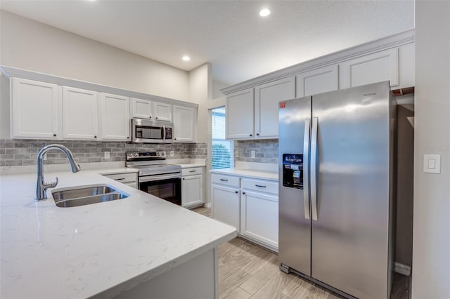 kitchen featuring light stone countertops, appliances with stainless steel finishes, tasteful backsplash, sink, and white cabinets