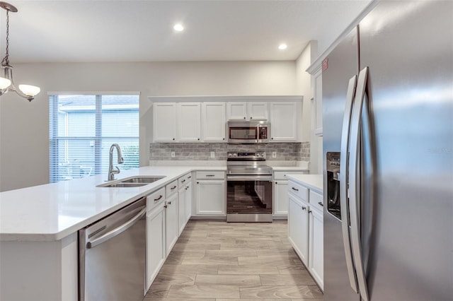 kitchen featuring appliances with stainless steel finishes, tasteful backsplash, sink, pendant lighting, and white cabinetry