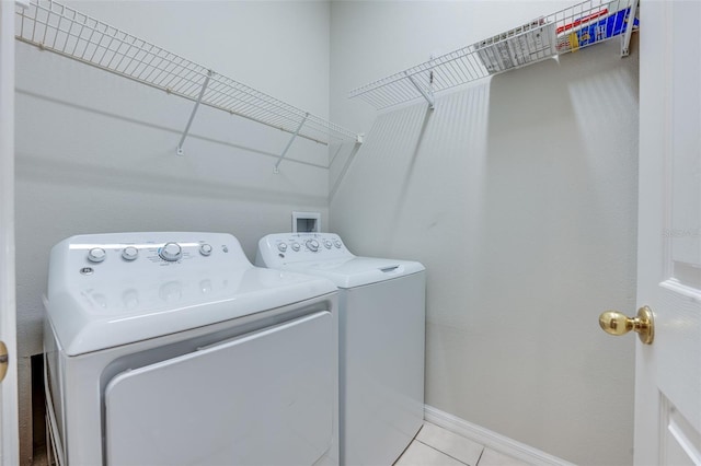 laundry area with independent washer and dryer and light tile patterned flooring