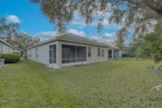 back of house featuring a lawn and a sunroom