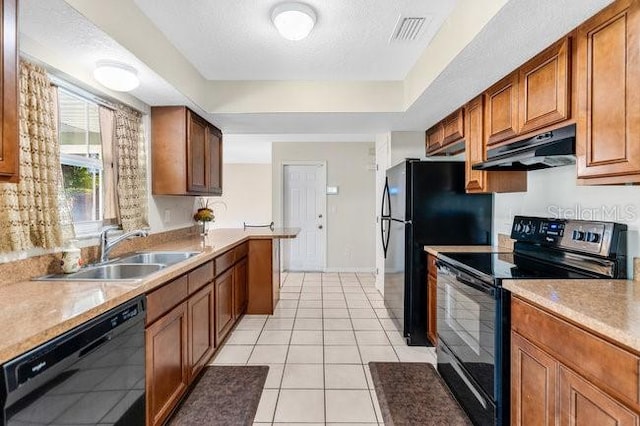 kitchen featuring sink, light tile patterned flooring, black appliances, and a textured ceiling