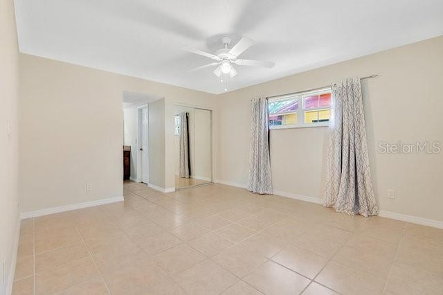 tiled empty room featuring ceiling fan