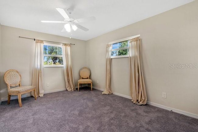 sitting room featuring ceiling fan and dark carpet