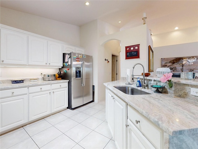 kitchen featuring stainless steel fridge, light tile patterned flooring, white cabinetry, and sink