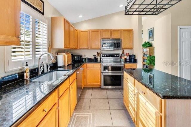 kitchen featuring light tile patterned floors, vaulted ceiling, sink, dark stone counters, and stainless steel appliances