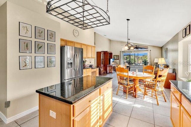 kitchen with light tile patterned floors, light brown cabinets, stainless steel fridge, and a center island