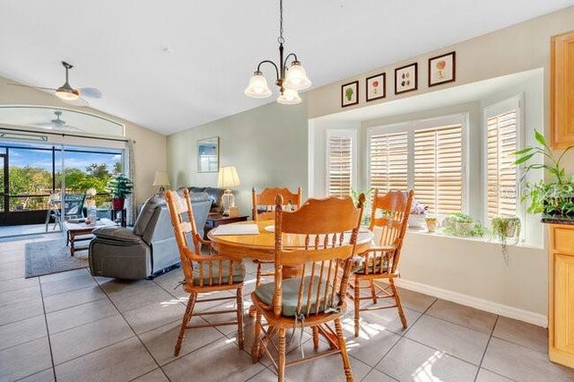 dining room with lofted ceiling, light tile patterned flooring, and ceiling fan with notable chandelier