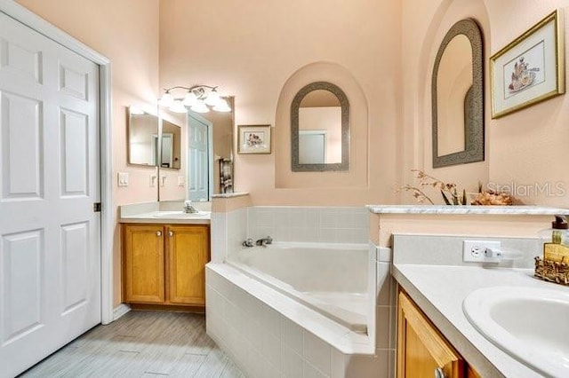 bathroom featuring tiled bath and vanity