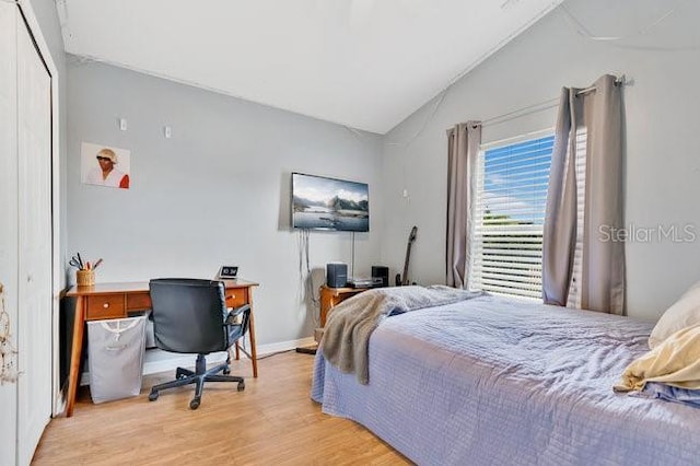 bedroom with light wood-type flooring, a closet, and lofted ceiling