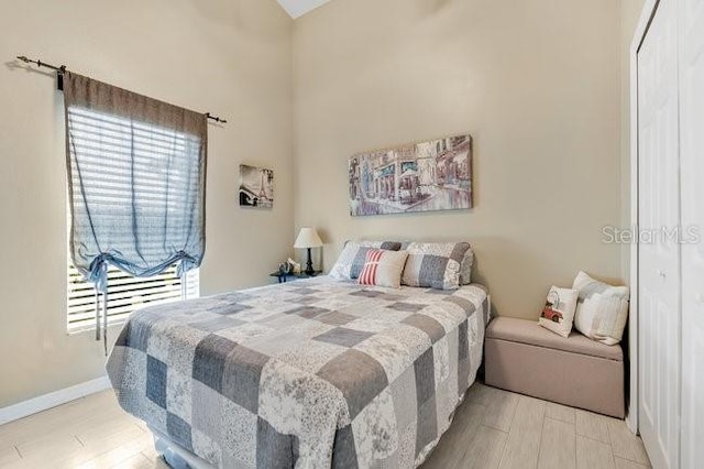 bedroom featuring light hardwood / wood-style flooring, a closet, and a high ceiling