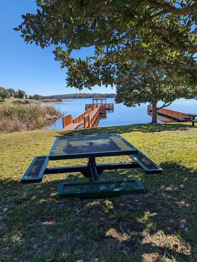 view of community featuring a dock, a yard, and a water view