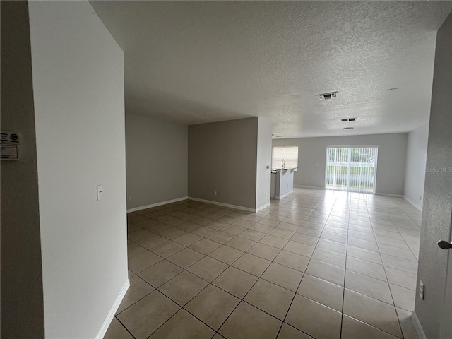 empty room featuring light tile patterned flooring and a textured ceiling