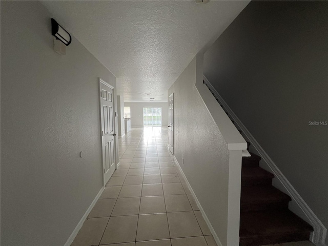 hall with light tile patterned floors and a textured ceiling