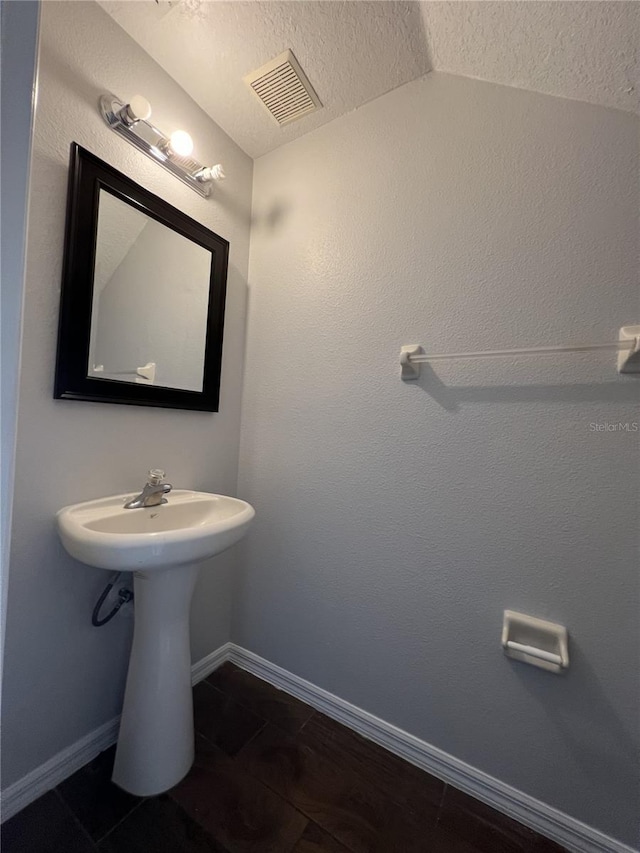 bathroom featuring a textured ceiling and vaulted ceiling