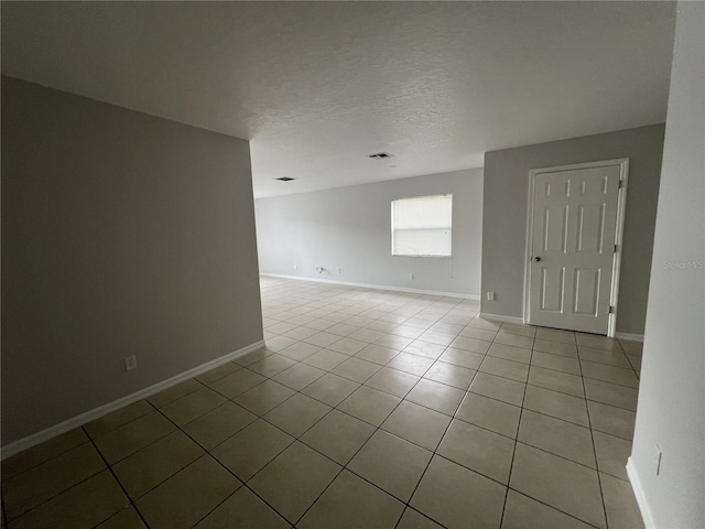 tiled empty room featuring a textured ceiling