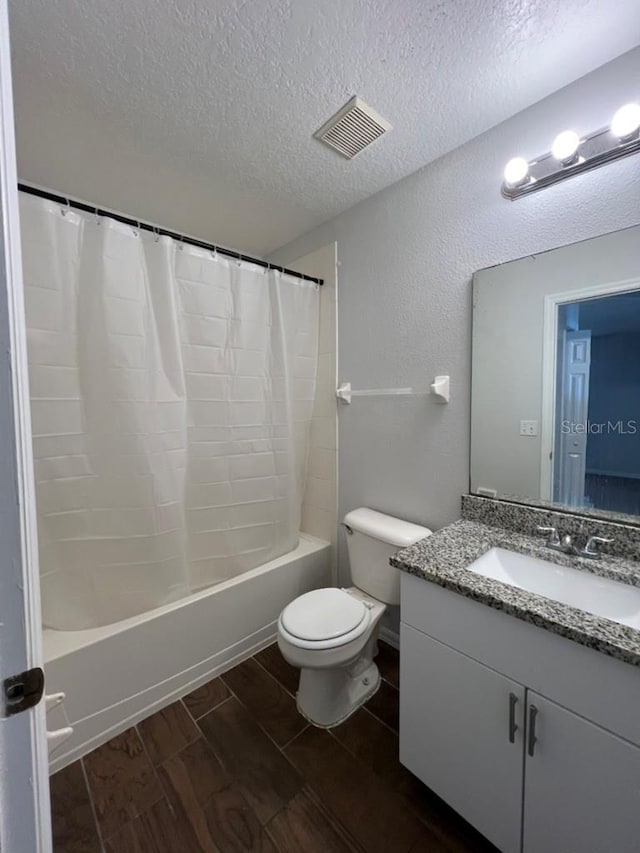 full bathroom featuring shower / tub combo, vanity, a textured ceiling, hardwood / wood-style flooring, and toilet