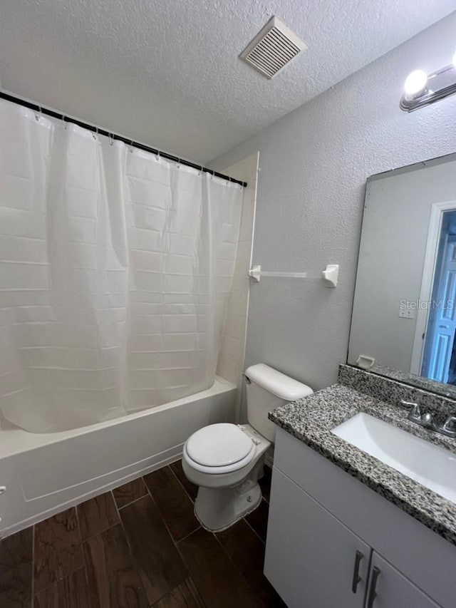 full bathroom featuring hardwood / wood-style floors, vanity, shower / bath combination with curtain, toilet, and a textured ceiling