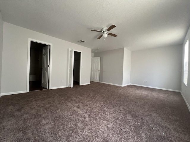 unfurnished bedroom with dark colored carpet, a textured ceiling, ensuite bath, and ceiling fan