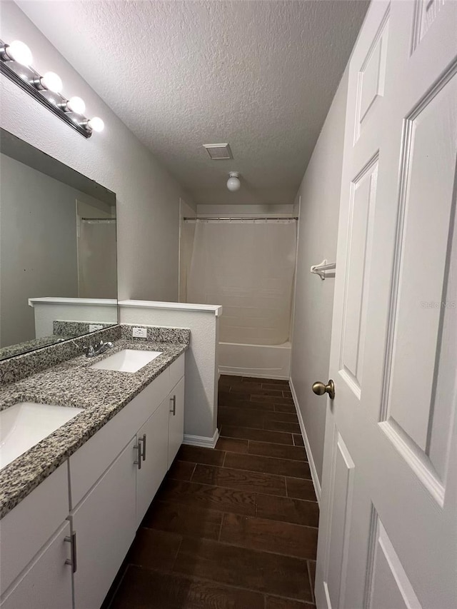 bathroom with hardwood / wood-style floors, vanity, tub / shower combination, and a textured ceiling