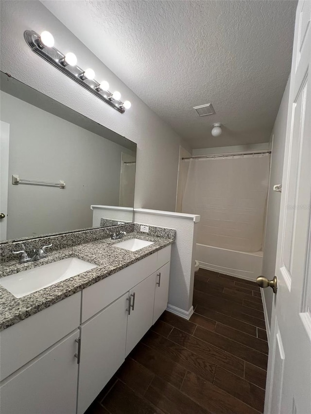 bathroom featuring shower / washtub combination, vanity, wood-type flooring, and a textured ceiling