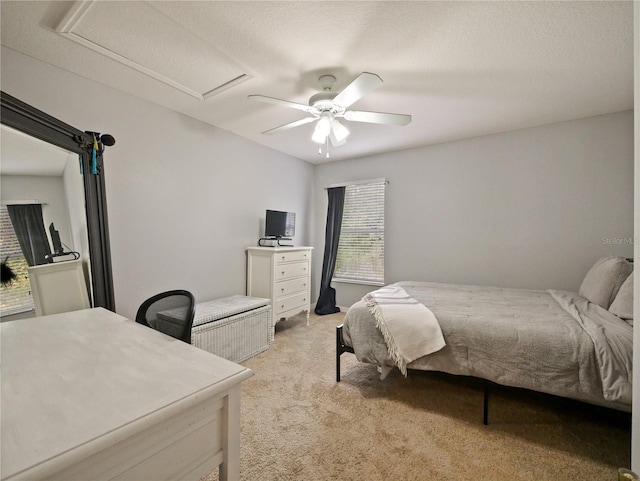 bedroom featuring ceiling fan, light colored carpet, and a textured ceiling