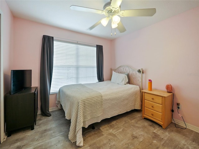 bedroom featuring multiple windows, hardwood / wood-style flooring, and ceiling fan